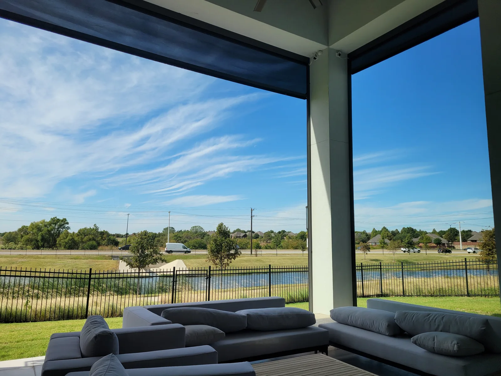 Motorized patio screen on a covered patio facing a backyard lake