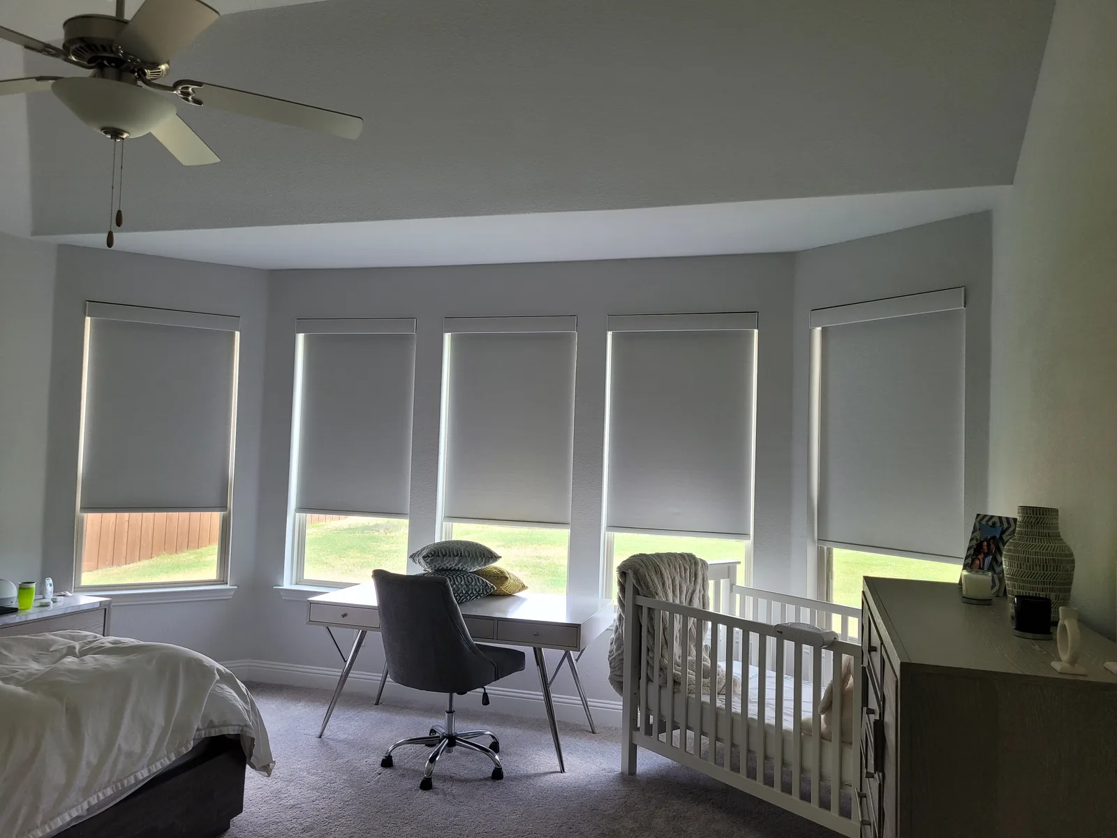 Roller shades on a bedroom bay window, lowered halfway