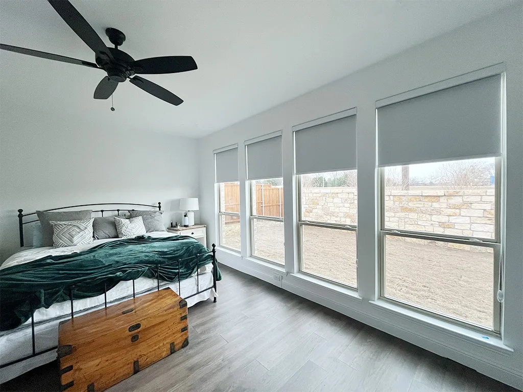 Roller shades raised halfway in a bright bedroom