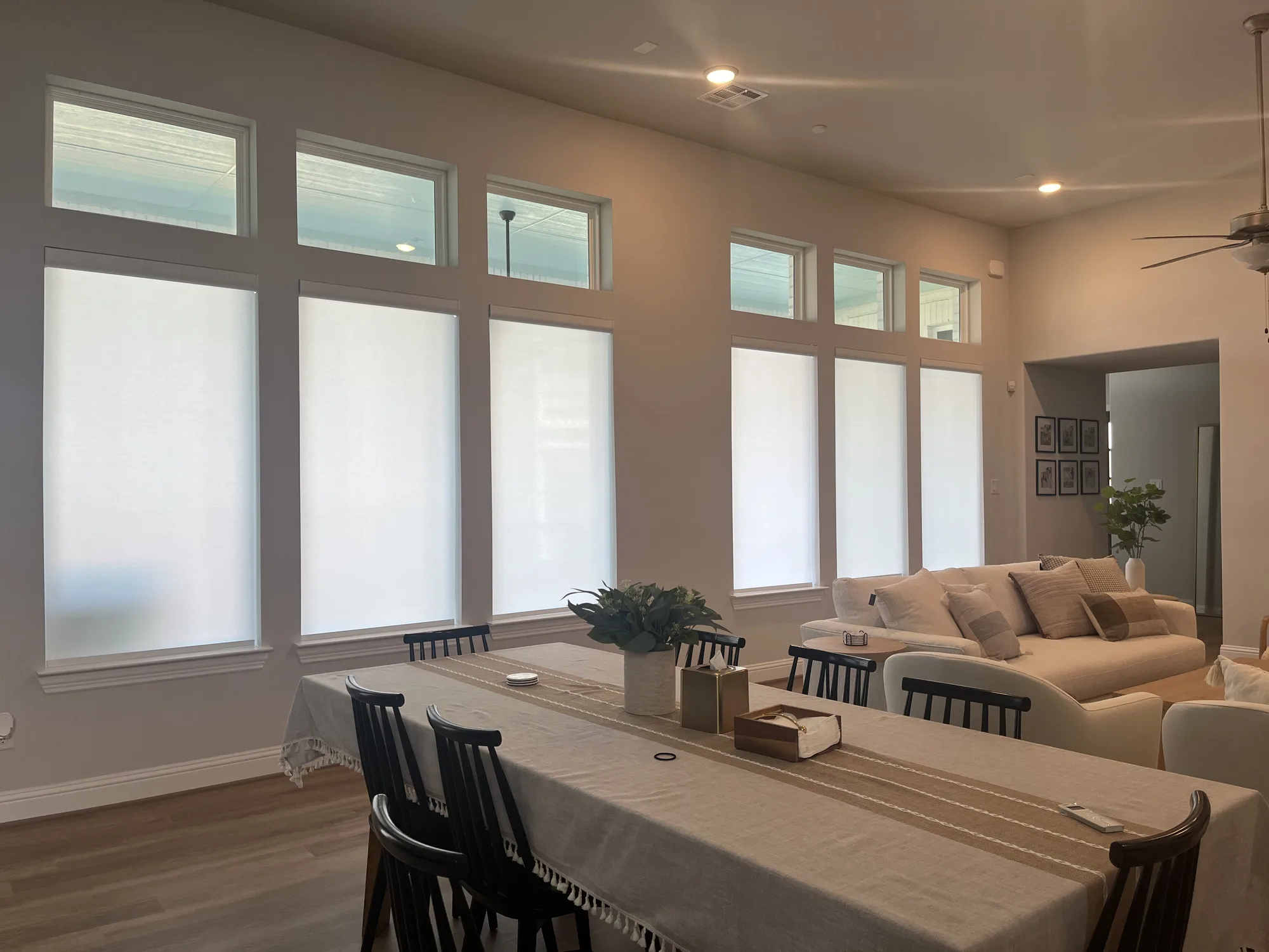 Roller shades below transom windows in an open dining and living room