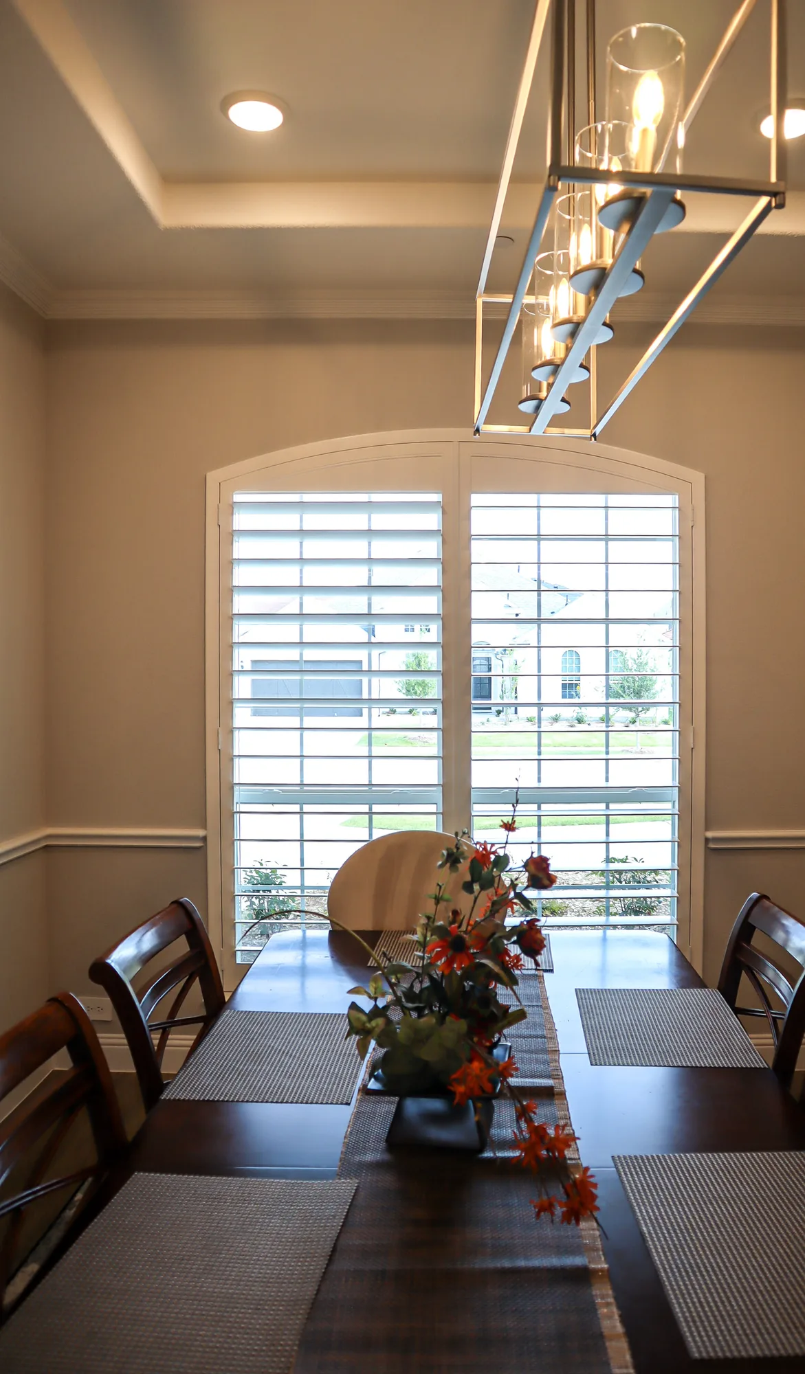 White plantation shutters on an arched dining room window