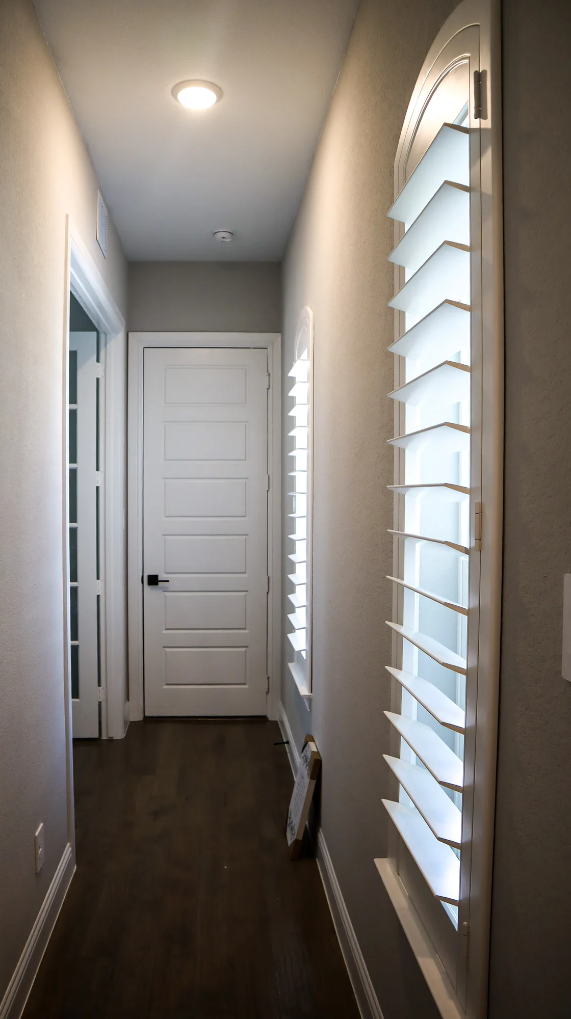 White plantation shutters on a tall arched hallway window