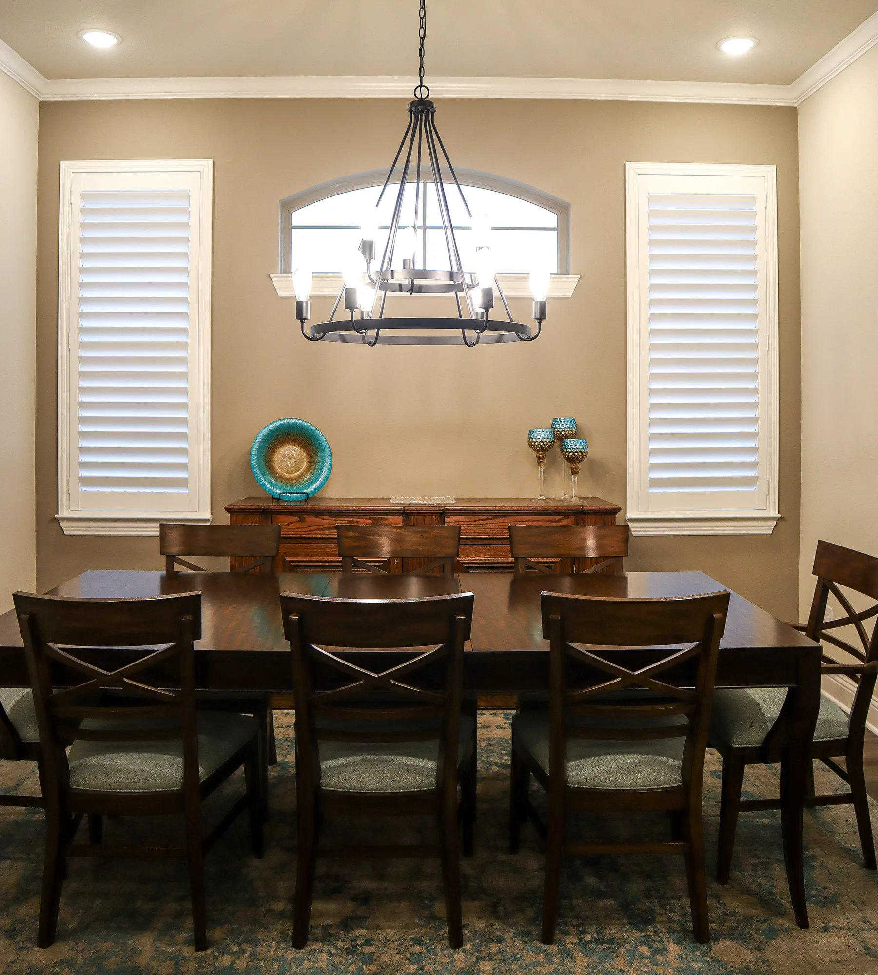 White plantation shutters on two dining room windows beside an open arch